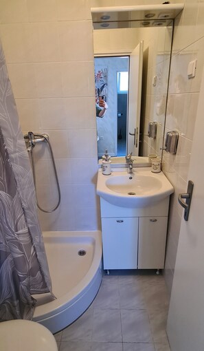 Un baño con ducha, lavamanos e inodoro.