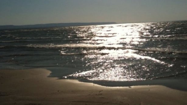 Een strand met zonlicht dat op het water weerkaatst.