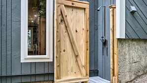 Une porte en bois avec une traverse diagonale, une fenêtre à cadre blanc et un mur en béton.