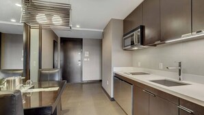 Une cuisine moderne équipée d’appareils électroménagers en acier inoxydable, d’une table à manger en verre et d’un four à micro-ondes encastré.