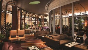 Eine geräumige Lobby mit modernen Möbeln, großen Fenstern und einer zentralen Treppe.