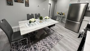 Una cocina moderna con encimera de mármol, electrodomésticos de acero inoxidable y un comedor con mesa y sillas de mármol.