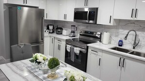 Una cocina moderna con armarios blancos, electrodomésticos de acero inoxidable, encimera de mármol y una decoración central.