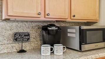 Une cuisine équipée d’une machine à café, de deux tasses et d’un panneau.