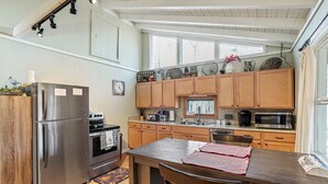 A kitchen with wooden cabinets, stainless steel appliances, a window, and a countertop with a red and white striped placemat. - Woodland Cottage | Secluded Hocking Hills Getaway (Laurelville)