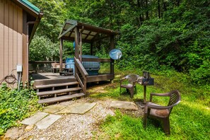 A rustic cabin with a wooden deck, a satellite dish, and a picnic table.