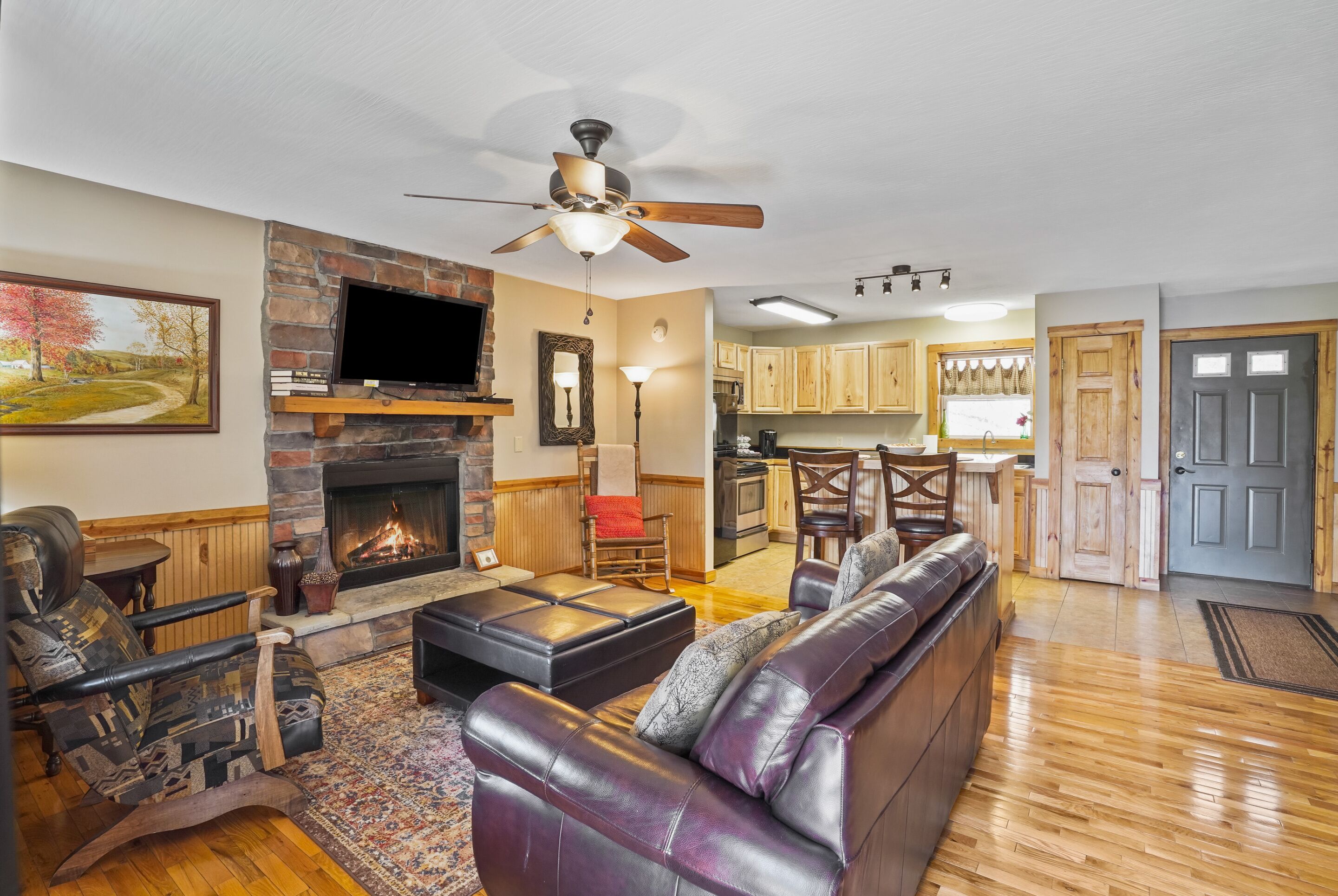 A living room with a fireplace, leather sofa, and a television.