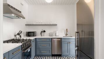 A modern kitchen with grey cabinets, stainless steel appliances, and a checkered floor.