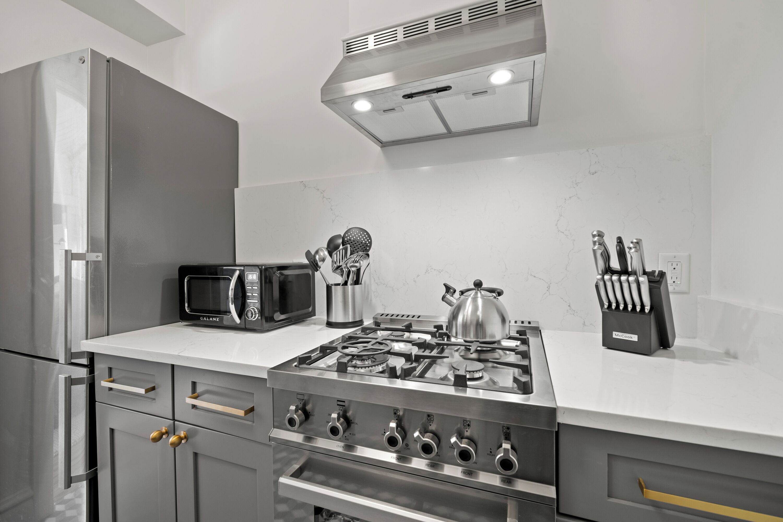 Una cucina moderna con elettrodomestici in acciaio inossidabile, piano cottura a gas e forno a microonde.