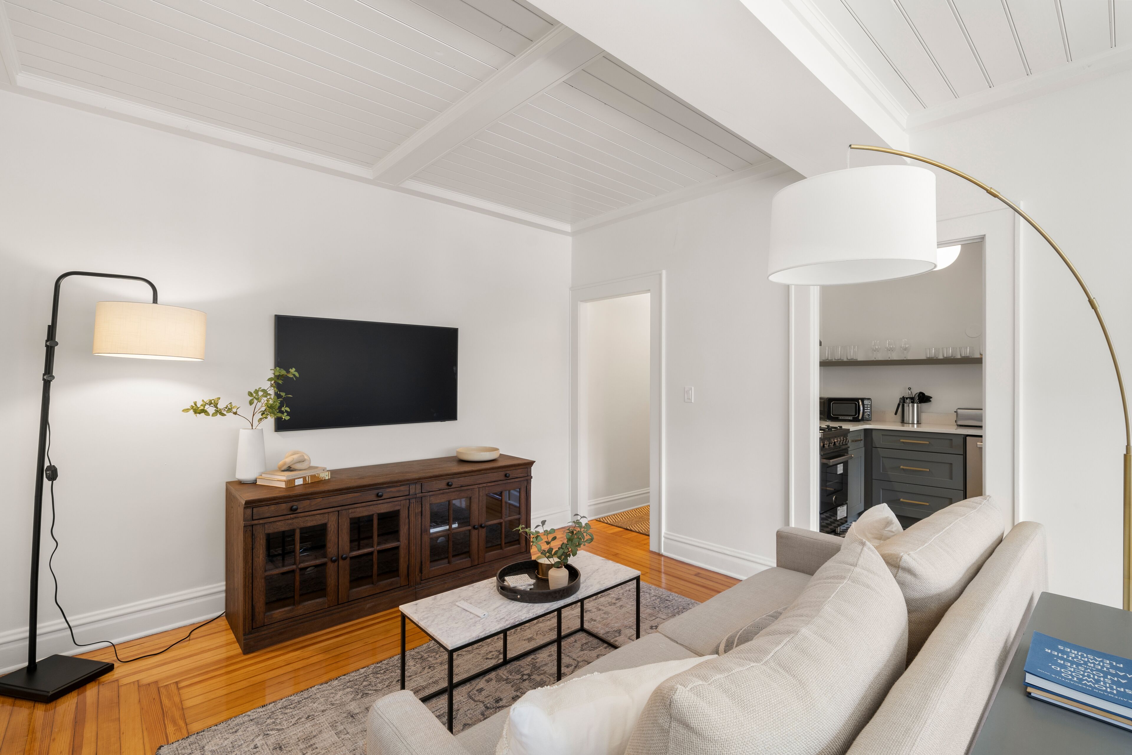 A modern living room with a flat-screen TV, dark wooden cabinet, beige sofa, and a coffee table.