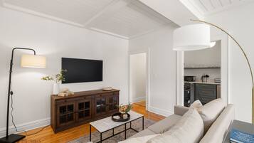 A modern living room with a flat-screen TV, dark wooden cabinet, beige sofa, and a coffee table.