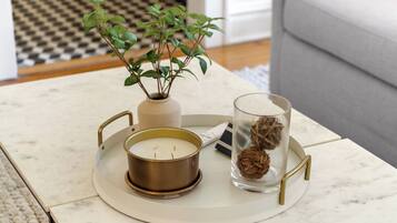 A marble table with a candle, a vase with a plant, and a glass container with dried flowers.