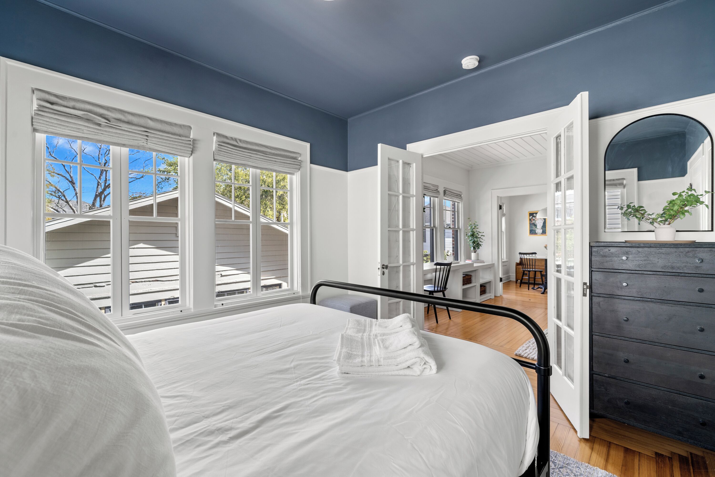 A bedroom with a bed, a dresser, and a view of the outside.