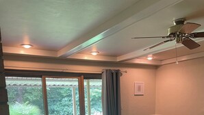 A spacious living room with a sectional sofa, a ceiling fan, and a sliding glass door leading to a patio.