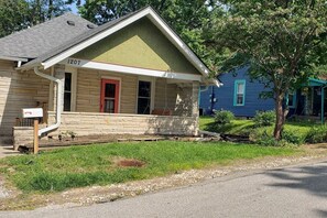 A single-story house with a green roof and a red door, number 1207, located at the end of a driveway. - Casa Bryan Park (Bloomington)