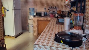 A compact kitchen with a refrigerator, microwave, water dispenser, and a blender.