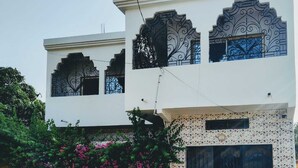 A two-story building with ornate black metal window frames, a tiled facade, and a black garage door.