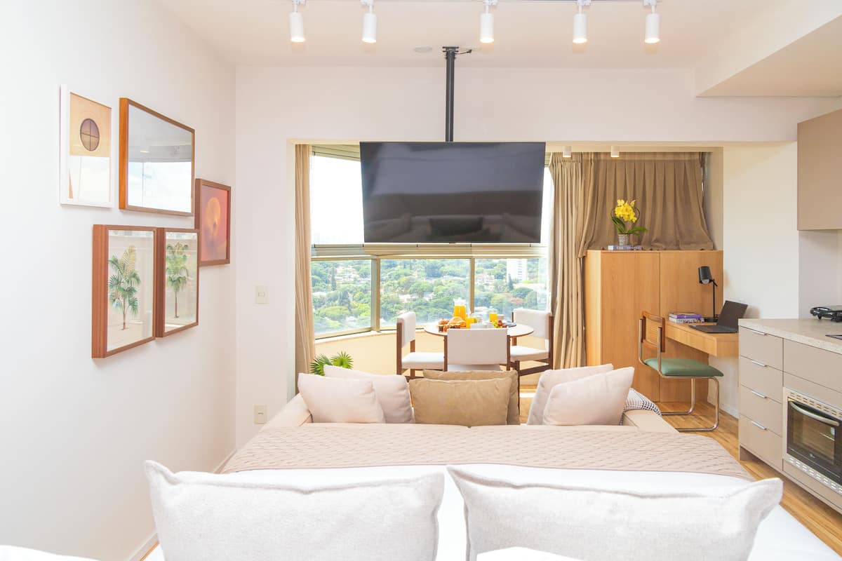 Una camera d'albergo moderna con un letto grande, un'area pranzo, una TV e vista sulla città.