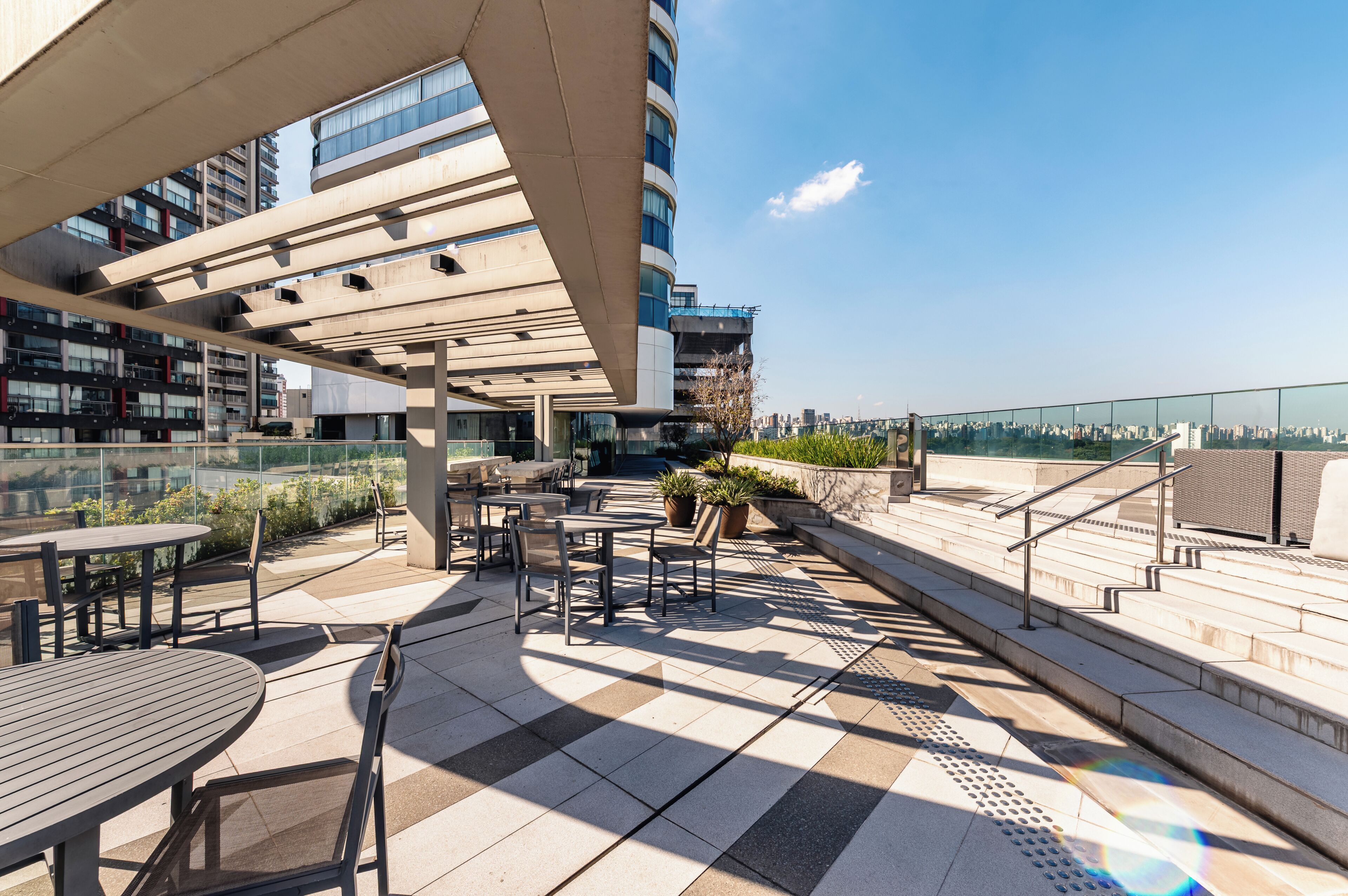 Una terraza en la azotea con asientos al aire libre, vistas a la ciudad y una estructura de edificio moderna.
