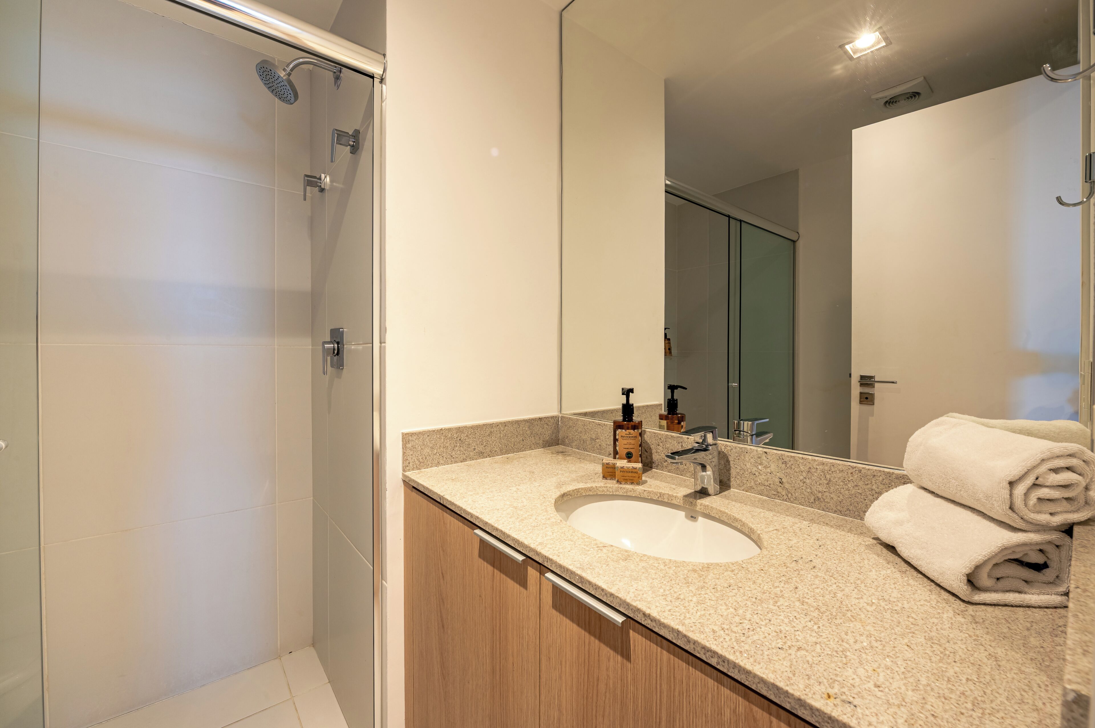 A modern bathroom with a sink, mirror, and shower.