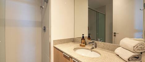 A modern bathroom with a sink, mirror, and shower.
