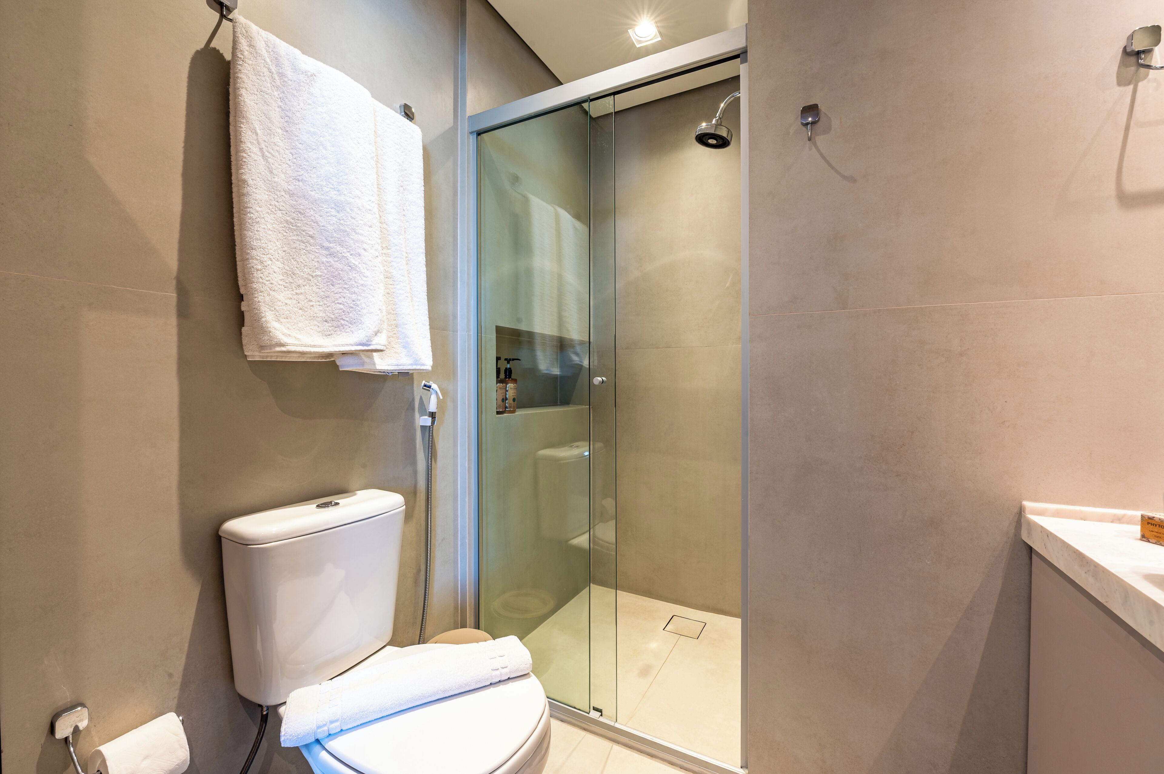 A modern bathroom with a glass-enclosed shower, a toilet, and a sink.