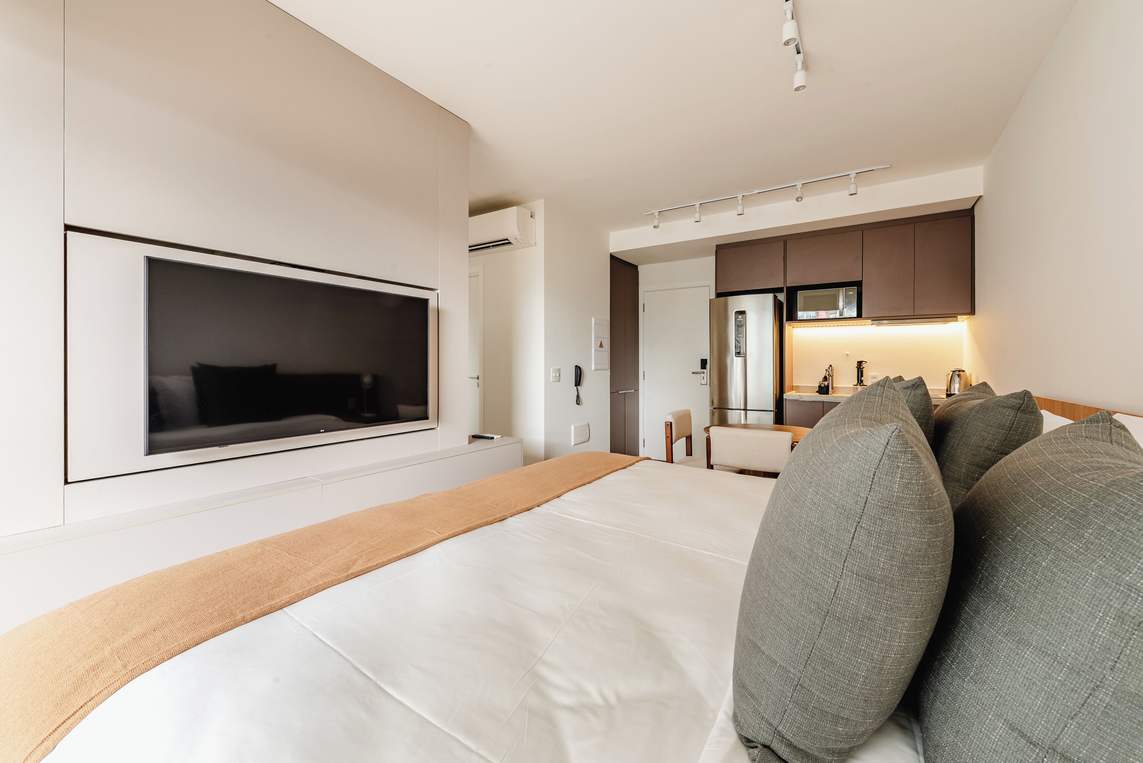 Une chambre d’hôtel moderne équipée d’un grand lit, d’une télévision, d’une kitchenette et d’une salle de bain.