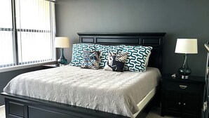 Una camera da letto con un letto, due comodini, una ventola a soffitto e una finestra con tende.