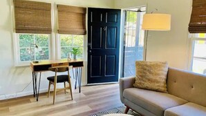 A room with a desk, two chairs, a sofa, and a black door.