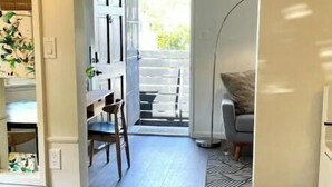 A hallway with a dining area, a trash bin, and a view of the outdoors.