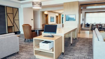 A modern hotel lobby with a reception desk, seating area, and a large window.