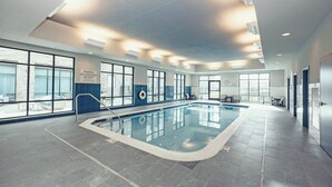 Una piscina interior con agua cristalina, paredes de azulejos y amplios ventanales que dejan entrar luz natural.