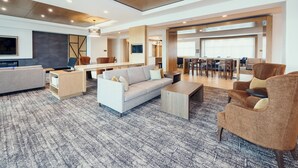Un amplio salón con sofá, sillones, una mesa de centro y una mesa de comedor.