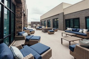 An outdoor patio area with wicker furniture, a fire pit, and a view of the building's exterior.