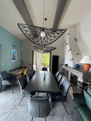Un comedor moderno con una mesa larga, varias sillas y una lámpara de techo con un diseño geométrico original.