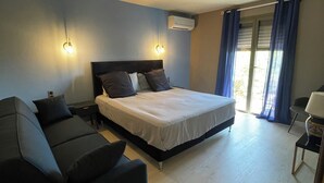 A bedroom with a bed, a sofa, a desk, and a window with curtains. - Villa "terre D'azur" Avec vue mer , Piscine, Jardin Clos, Rénovée (La Croix-Valmer)