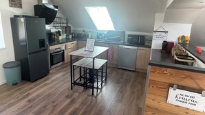Une cuisine moderne avec un coin repas, équipée d’un réfrigérateur, d’un four, d’un four à micro-ondes et d’un lave-vaisselle.