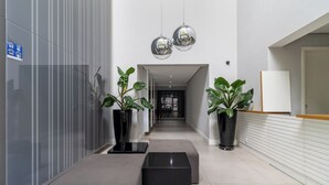 Een moderne hal met een bank, plantenbakken en een receptiebalie.