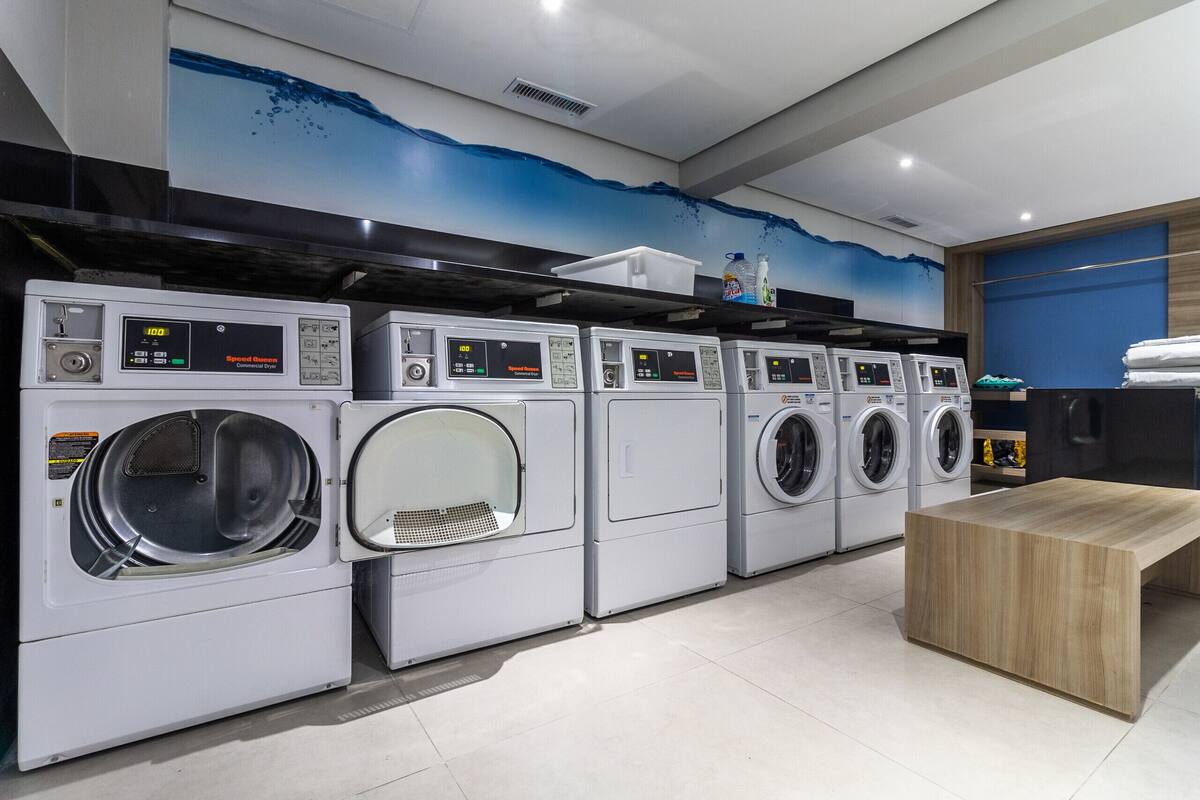A row of front-loading washing machines in a commercial setting.
