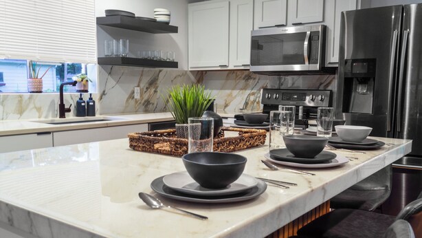 A modern kitchen with a marble countertop, stainless steel appliances, and a central island with seating.