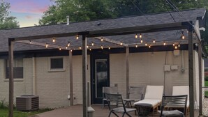 A covered patio with outdoor seating, a wooden deck, and string lights.
