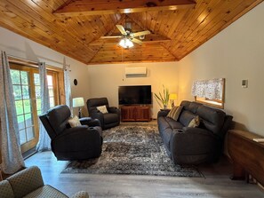 A living room with a ceiling fan, a large flat-screen TV, and two sofas. - Chucle Homestead - Charming 3 bdrm, 2 bath ranch home (Maryland)