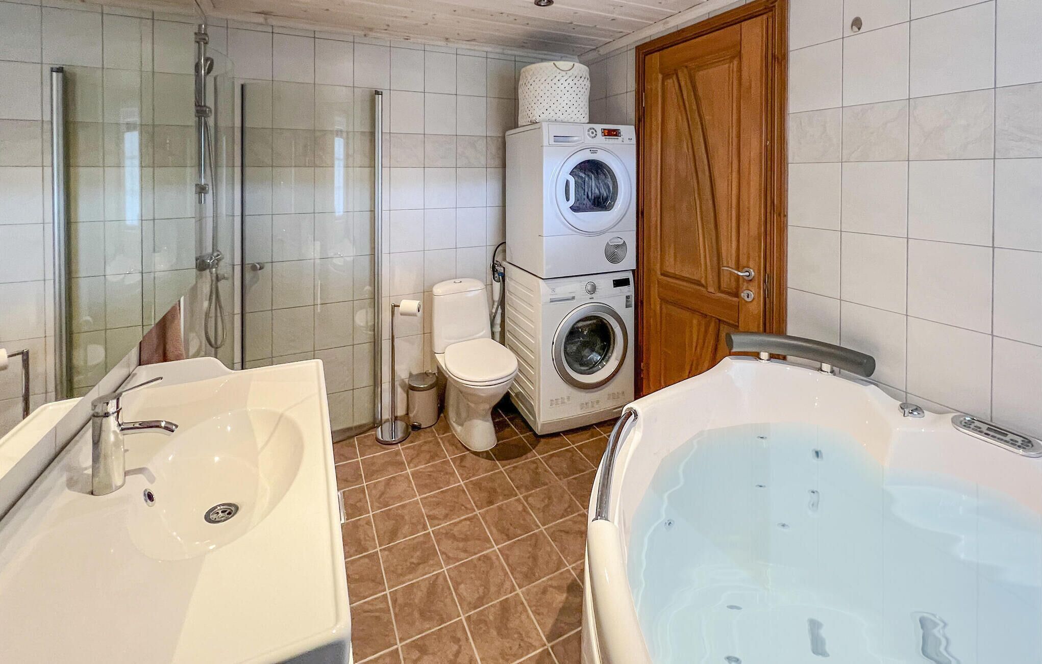 A bathroom with a shower, two sinks, a toilet, a washing machine, and a bathtub.