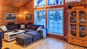 A cozy cabin interior with a sectional sofa, a small table, and a cabinet with glassware. - Beautiful home in Sjusjøen with sauna (Sjusjøen)