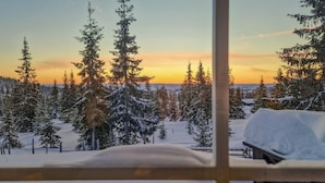 A snowy landscape with evergreen trees and a sunset view through a window. - Beautiful home in Sjusjøen with sauna (Sjusjøen)