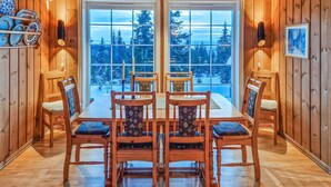 A wooden interior with a dining table and chairs, large windows with a view of snow-covered trees. - Beautiful home in Sjusjøen with sauna (Sjusjøen)