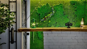 Un mostrador de recepción con un muro cubierto de musgo verde, una encimera de madera y un farol.