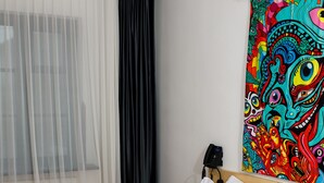 Habitación de hotel con dos camas, un tapiz colorido, un teléfono y cortinas translúcidas.
