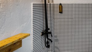 Un baño con una bañera blanca, un inodoro y una ducha. Hay un estante de madera sobre el inodoro.