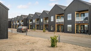 A row of modern, dark-colored buildings with balconies and large windows, likely part of a residential or hotel complex. - Havnehusene, Lejl. 40 (Slagelse)
